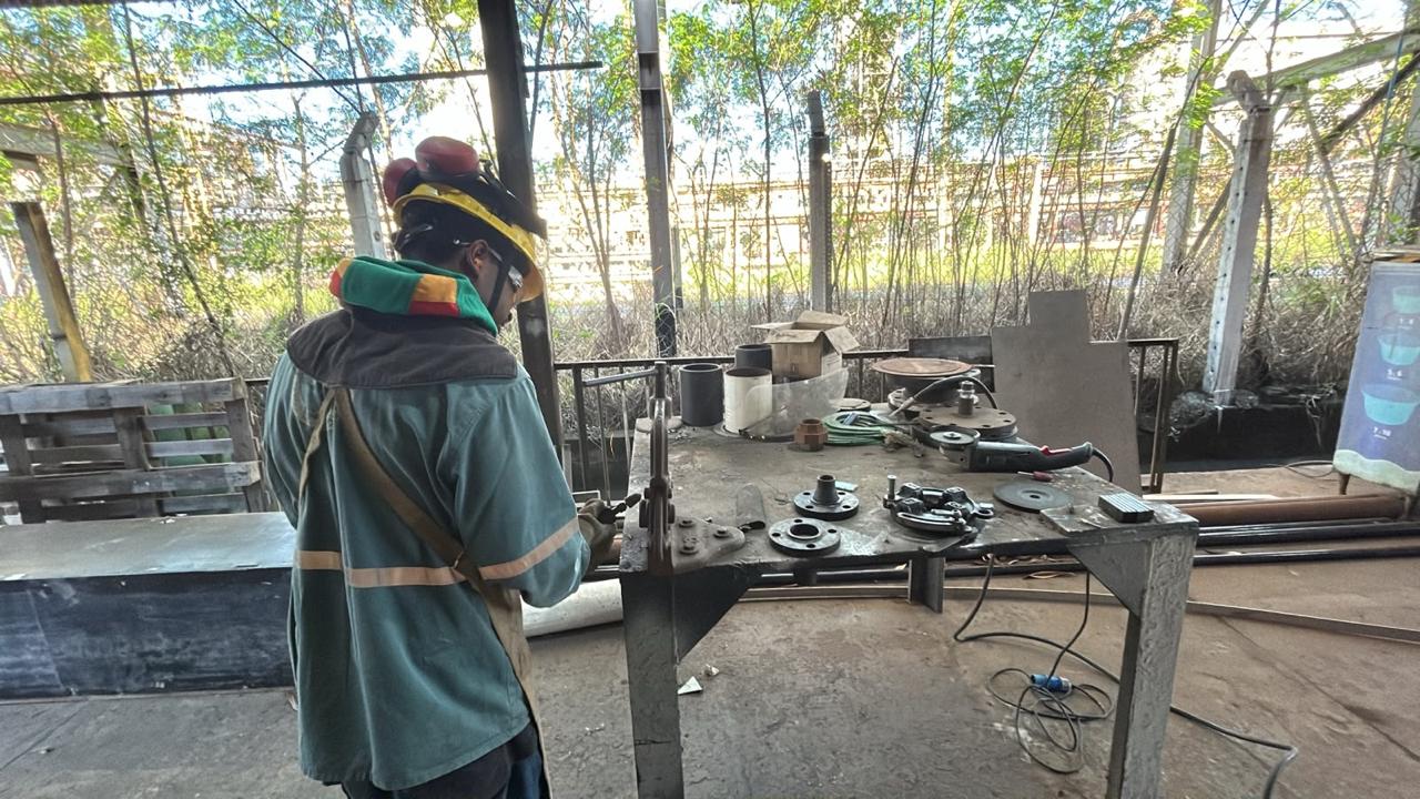 Profissional fabricando e ajustando componentes industriais em bancada