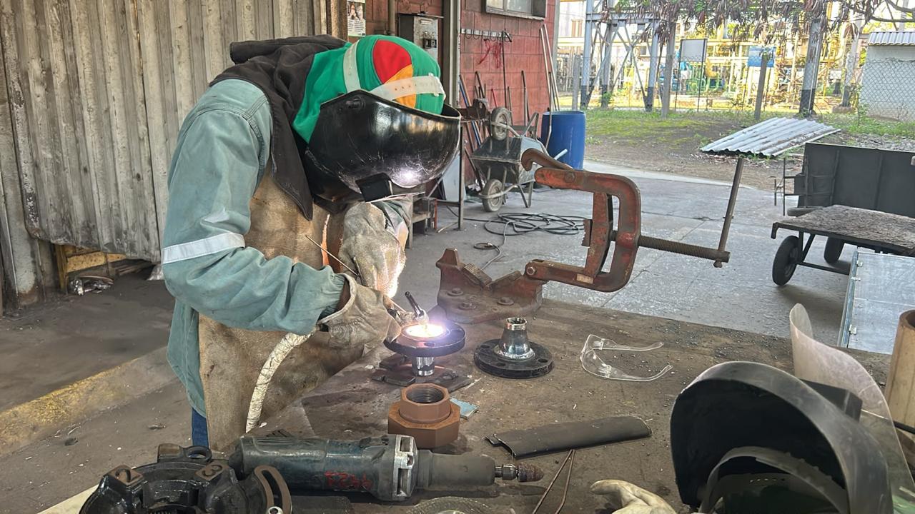Profissional realizando soldagem de componente industrial em bancada